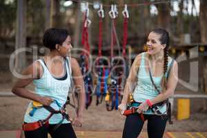 Female friends getting their belt tied to perform zip line