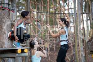 Friends climbing a net during obstacle course in adventure park