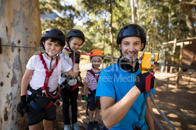 Kids and instructor getting ready to zip line in park
