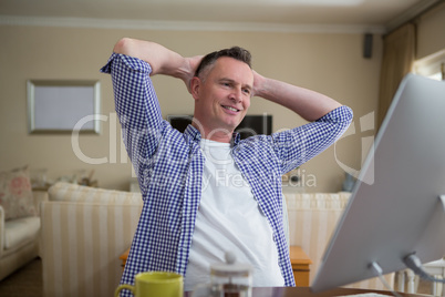 Man relaxing with hands behind head in living room