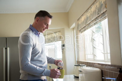 Man pouring coffee into cup in kitchen