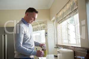 Man pouring coffee into cup in kitchen