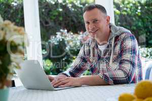 Smiling man using laptop in porch