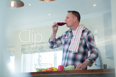 Man drinking red wine in kitchen