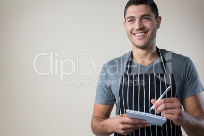 Smiling waiter writing down an order in the notepad