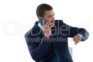 Businessman checking time while talking on mobile phone