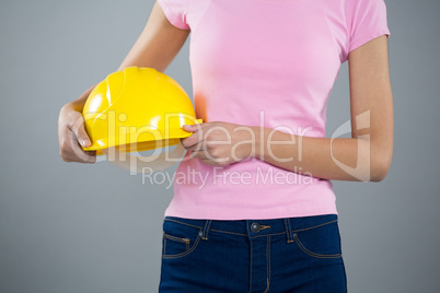 Woman holding hard hat against grey background