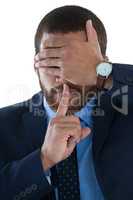 Businessman covering his eyes with finger on lips
