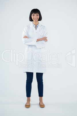 Doctor standing with arms crossed against white background