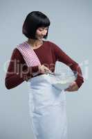 Female chef mixing flour in bowl with whisk
