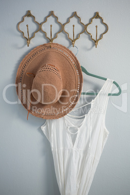 Hat and dress hanging against white wall