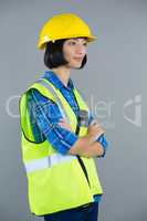 Female architect standing with arms crossed against grey background