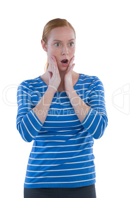 Woman with shocked facial expression standing with hand on face