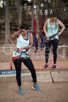 Female friends getting their belt tied to perform zip line