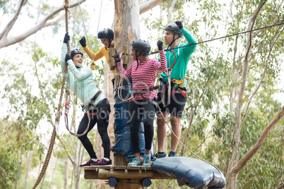 Friends enjoying zip line adventure in park on a sunny day