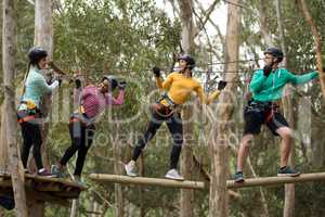 Friends enjoying zip line adventure in park