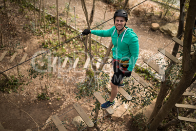 Man walking on rope bridge in adventure park