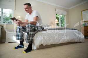 Man using digital tablet on bed in bedroom