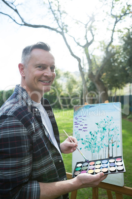 Man painting on canvas in garden