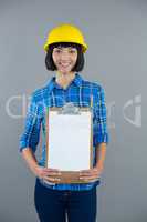 Female architect holding clipboard against grey background