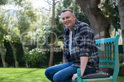 Smiling man sitting on bench in garden