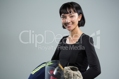 Female architect holding helmet and gloves against white background