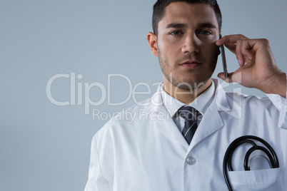 Doctor talking on the mobile phone against white background