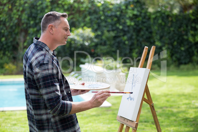 Man painting on canvas in garden