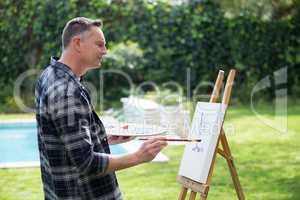 Man painting on canvas in garden