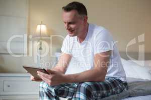 Man using digital tablet on bed in bedroom
