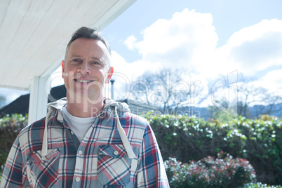 Smiling man standing in porch on a sunny day