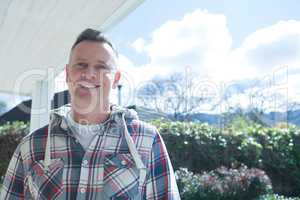 Smiling man standing in porch on a sunny day