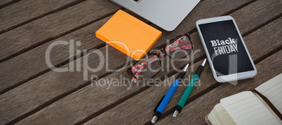 Composite image of mobile phone, laptop, pen, sticky note, spectacles and organizer on wooden plank