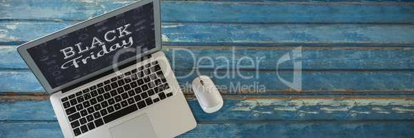 Composite image of laptop and mouse on wooden table