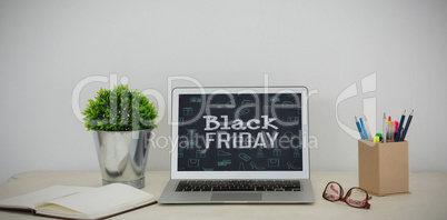 Composite image of laptop, pot pant, pencil holder, spectacles and organizer on table