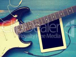 Vintage guitar with earphones on wood