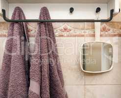 hanging objects in the bathroom: two towels and a white mirror