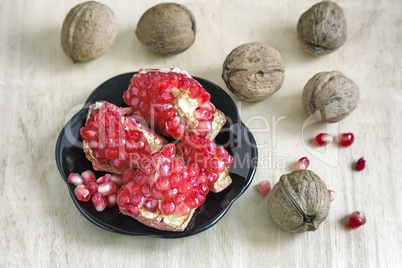 Pomegranate fruits on the plate and walnuts.