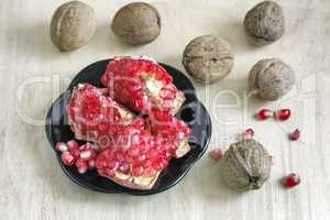 Pomegranate fruits on the plate and walnuts.