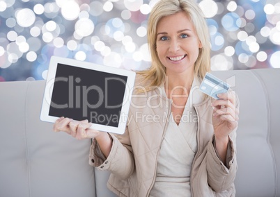 Woman holding tablet with bank card and sparkling lights background