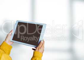 Hands holding tablet with bright windows background