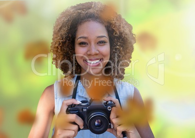 Woman with camera in forest with leaves