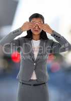 Businesswoman holding hands over eyes in city