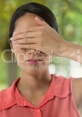 Woman holding hand over eyes in nature