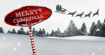 Merry Christmas text on Wooden signpost in Christmas Winter landscape and Santa's sleigh and reindee