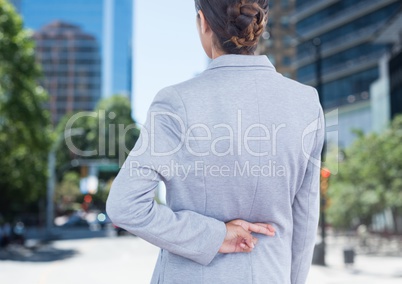 Businesswoman with fingers crossed in city