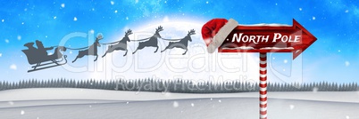 North Pole text on Wooden signpost in Christmas Winter landscape and Santa's sleigh and reindeer's