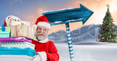 Santa holding gifts and Wooden signpost in Christmas Winter landscape with Christmas tree