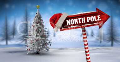 North Pole on Wooden signpost in Christmas Winter landscape and Santa hat with Christmas tree