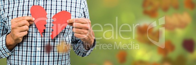 Man holding broken heart in forest with leaves